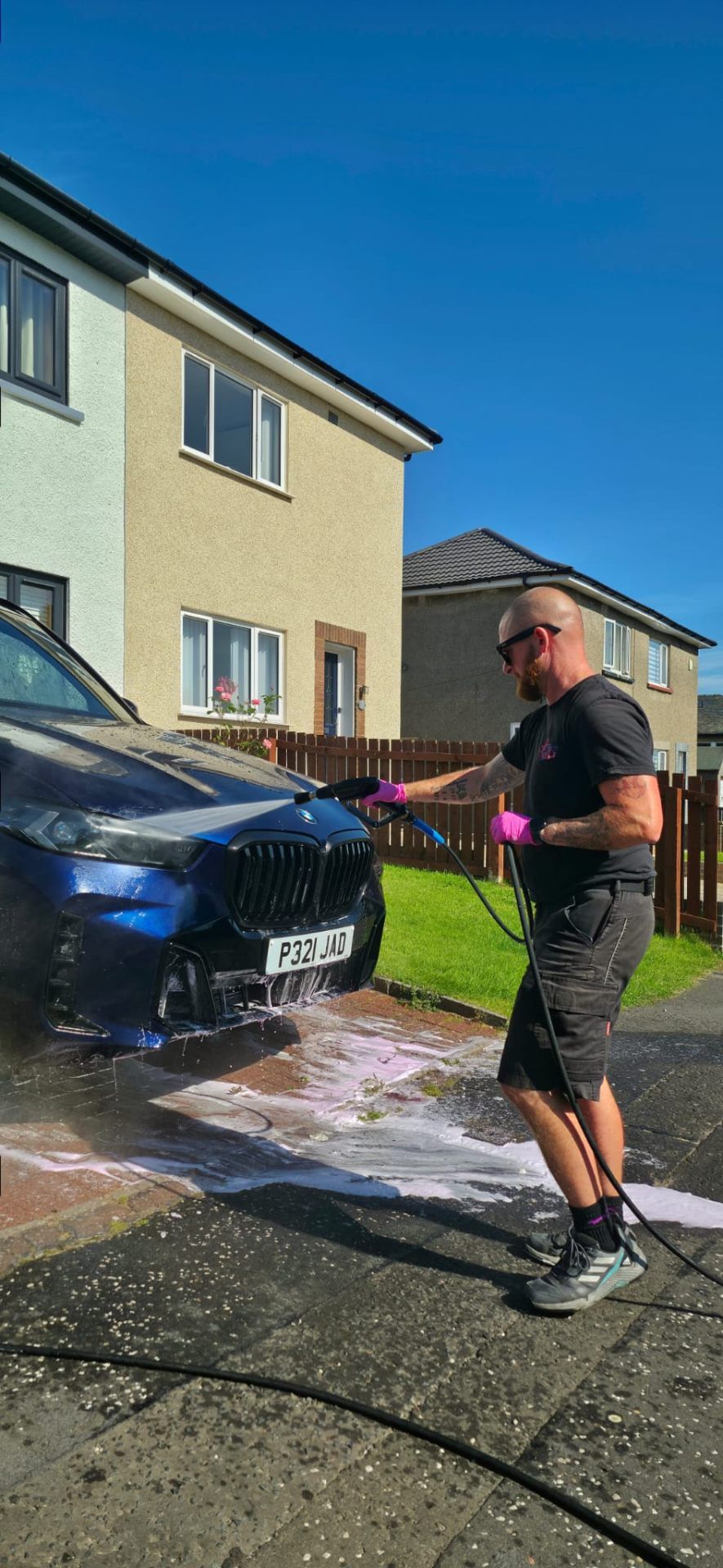 Owner pressure washing BMW — mobile service in action