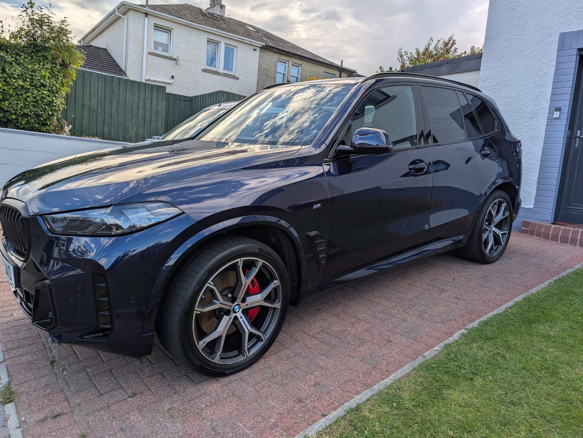 Dark BMW X5 side view on driveway after full detail